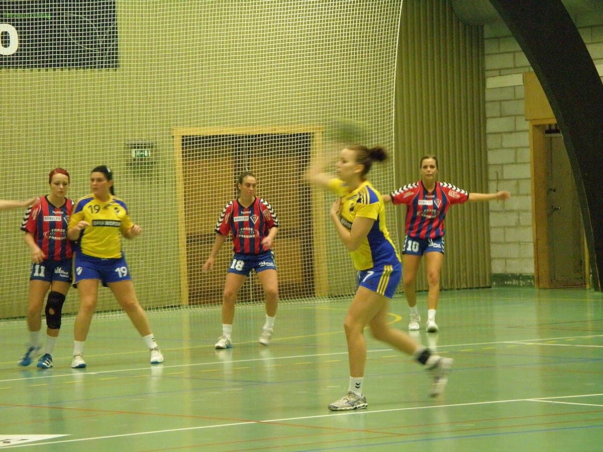 Women's handball action, player throwing toward goal